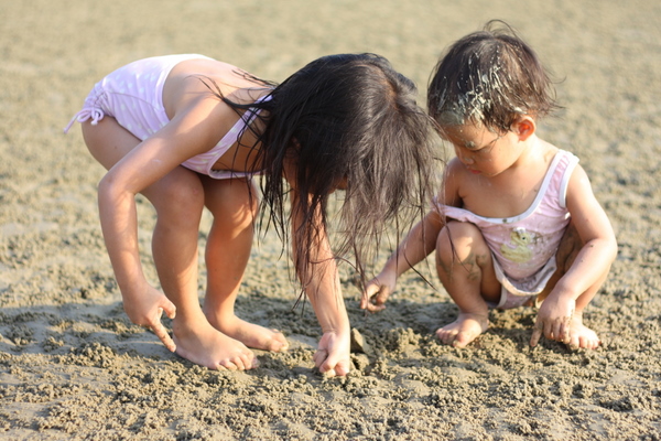 Zara showing Zaria how to dig for crabs